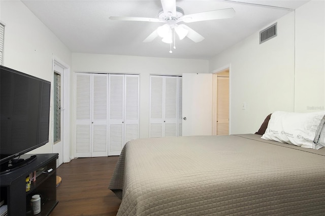 bedroom featuring ceiling fan, dark hardwood / wood-style flooring, and two closets