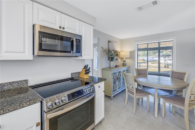 kitchen with dark stone counters, appliances with stainless steel finishes, and white cabinetry