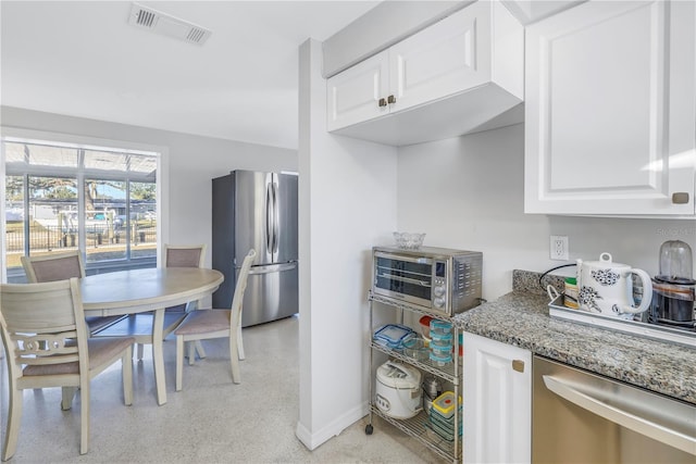 kitchen with appliances with stainless steel finishes, white cabinetry, and stone countertops