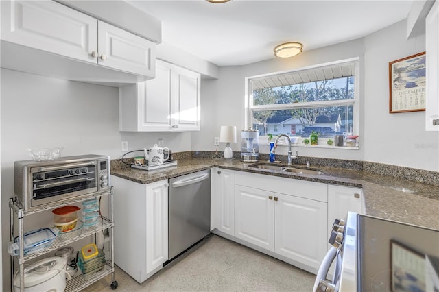 kitchen with appliances with stainless steel finishes, white cabinets, dark stone countertops, and sink