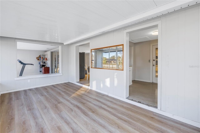 spare room featuring light wood-type flooring and wooden walls