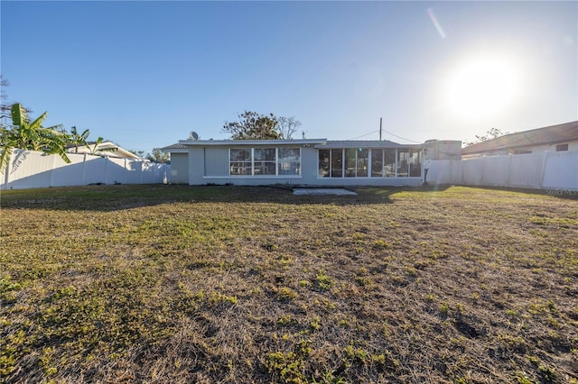 back of property with a yard and a sunroom