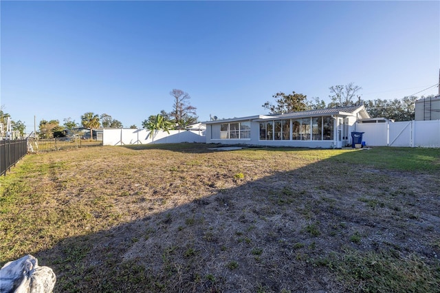 back of property featuring a sunroom and a lawn