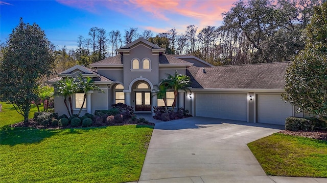 mediterranean / spanish-style home with driveway, a front lawn, an attached garage, and stucco siding