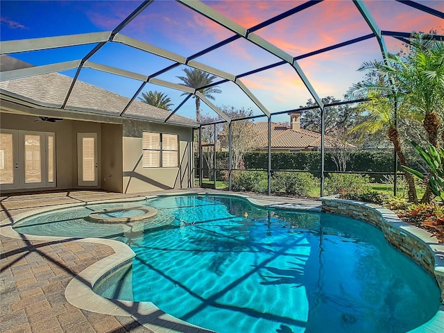 view of swimming pool with glass enclosure, a pool with connected hot tub, ceiling fan, and a patio