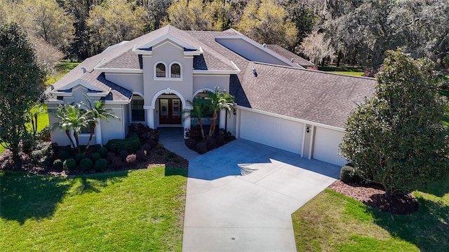 view of front of home with roof with shingles, an attached garage, french doors, a front yard, and stucco siding