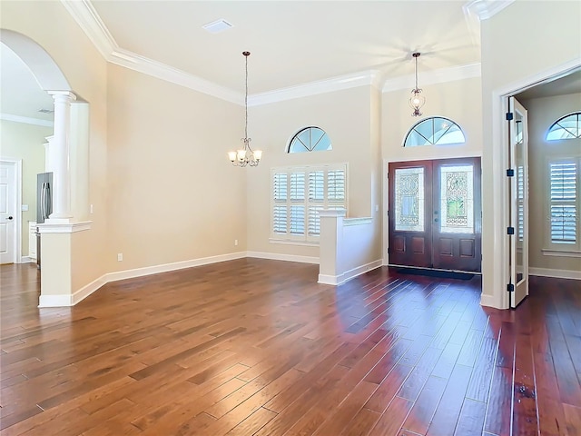 foyer with arched walkways, dark wood-style flooring, decorative columns, and crown molding