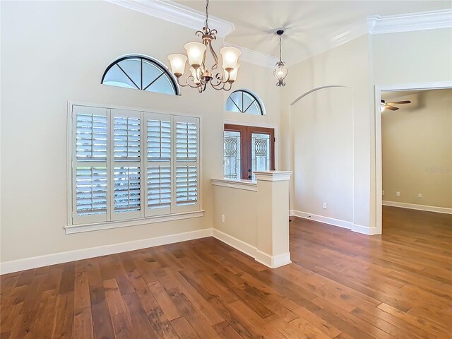 empty room with baseboards, crown molding, and wood finished floors