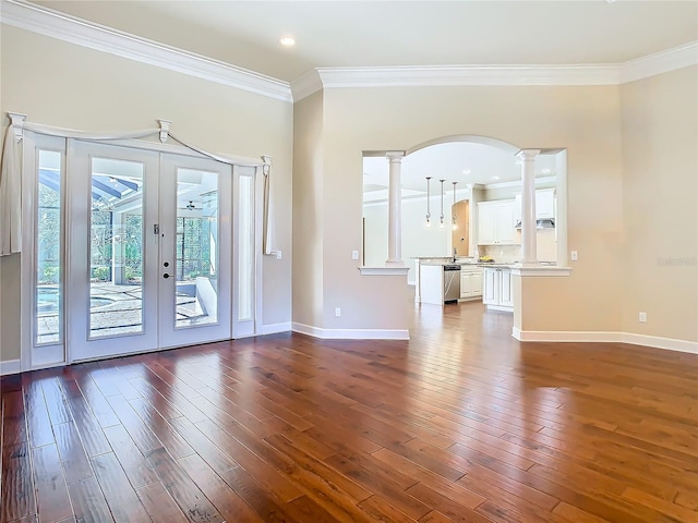 interior space with ornamental molding, baseboards, dark wood finished floors, and ornate columns