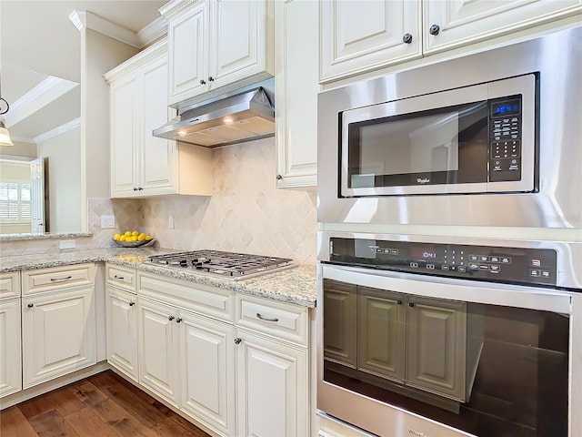 kitchen featuring crown molding, appliances with stainless steel finishes, decorative backsplash, and under cabinet range hood