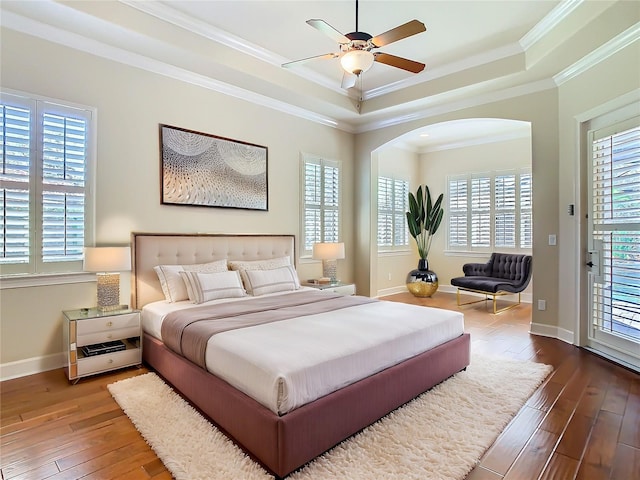 bedroom with baseboards, hardwood / wood-style flooring, access to exterior, a tray ceiling, and crown molding