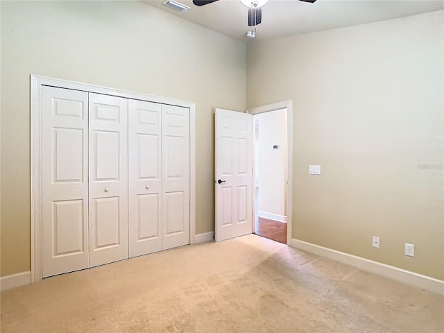 unfurnished bedroom featuring a ceiling fan, baseboards, a closet, and light colored carpet