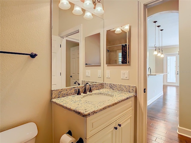 bathroom featuring crown molding, toilet, vanity, baseboards, and hardwood / wood-style flooring