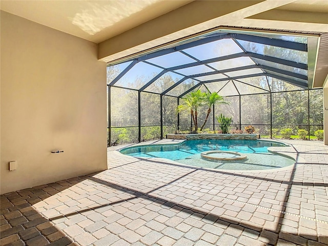 view of pool featuring a lanai, a pool with connected hot tub, and a patio