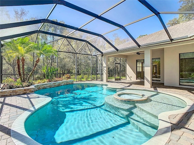 view of swimming pool featuring glass enclosure, a pool with connected hot tub, a ceiling fan, and a patio