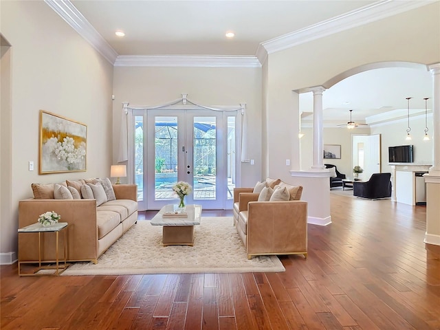 living room featuring decorative columns, arched walkways, hardwood / wood-style floors, crown molding, and french doors