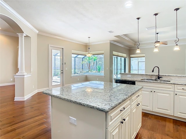 kitchen with arched walkways, decorative columns, dark wood-type flooring, a sink, and dishwasher