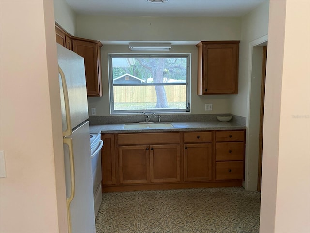 kitchen with sink, white appliances, and light tile patterned flooring