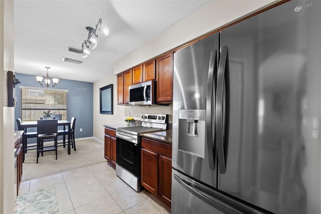 kitchen with a notable chandelier, hanging light fixtures, stainless steel appliances, a textured ceiling, and light tile patterned floors