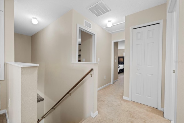 hallway featuring a textured ceiling and light colored carpet