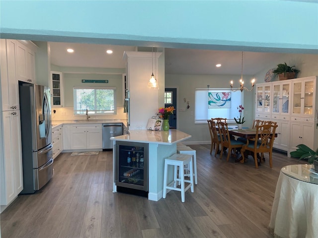 kitchen with a center island, beverage cooler, white cabinetry, appliances with stainless steel finishes, and sink