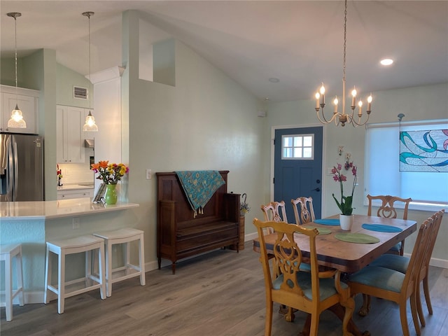 dining room featuring lofted ceiling, hardwood / wood-style floors, and a notable chandelier