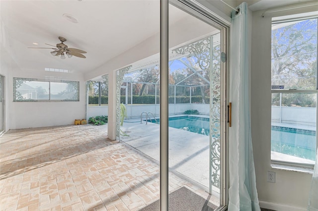 unfurnished sunroom with ceiling fan, vaulted ceiling, and a healthy amount of sunlight