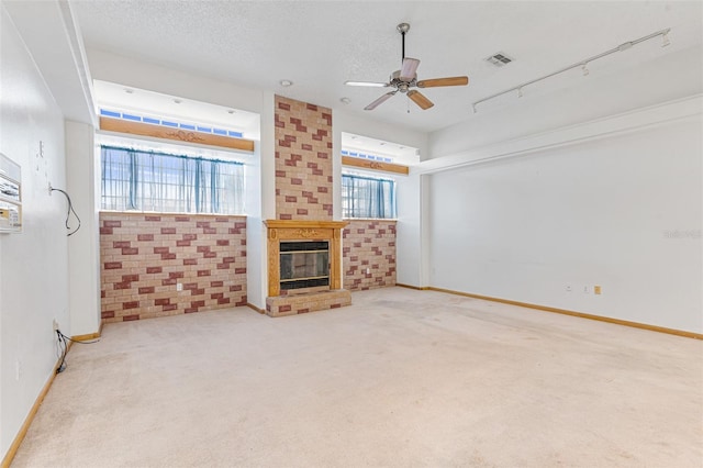 unfurnished living room with ceiling fan, track lighting, carpet floors, and a textured ceiling