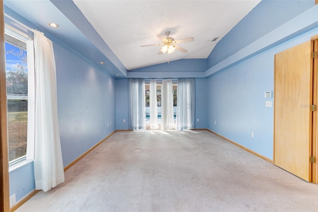 empty room with light carpet, a textured ceiling, vaulted ceiling, and ceiling fan