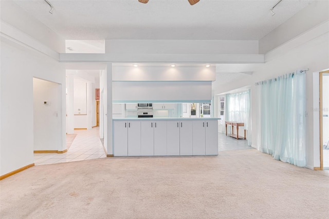 unfurnished living room with light carpet, rail lighting, and ceiling fan