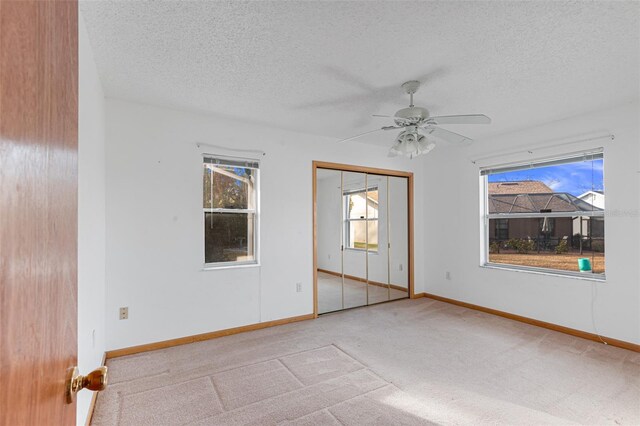 spare room featuring ceiling fan, light carpet, and a textured ceiling