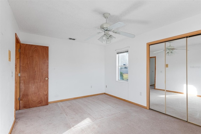 unfurnished bedroom with ceiling fan, light colored carpet, a closet, and a textured ceiling