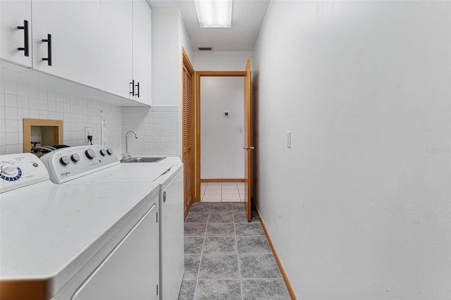 clothes washing area featuring washer and dryer, sink, cabinets, light tile patterned floors, and a textured ceiling