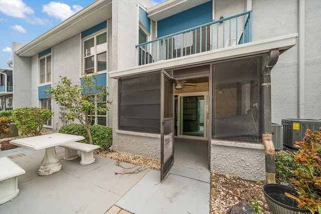 entrance to property with central AC unit, a balcony, and a patio