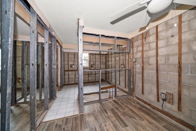 basement featuring ceiling fan and a textured ceiling