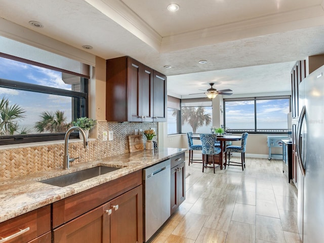 kitchen with ceiling fan, sink, light stone counters, and appliances with stainless steel finishes