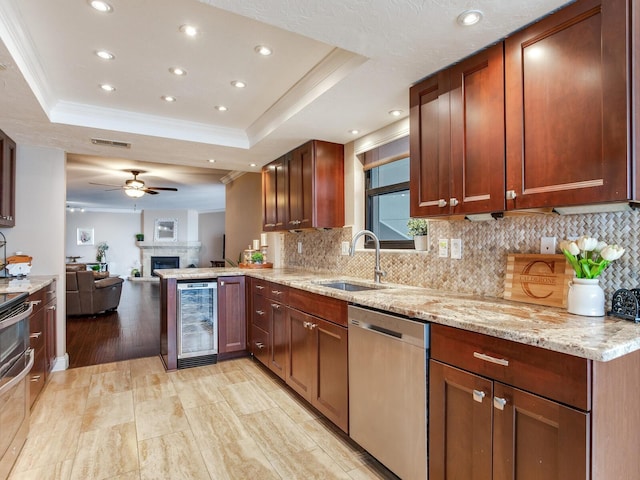 kitchen with a tray ceiling, sink, beverage cooler, and dishwasher