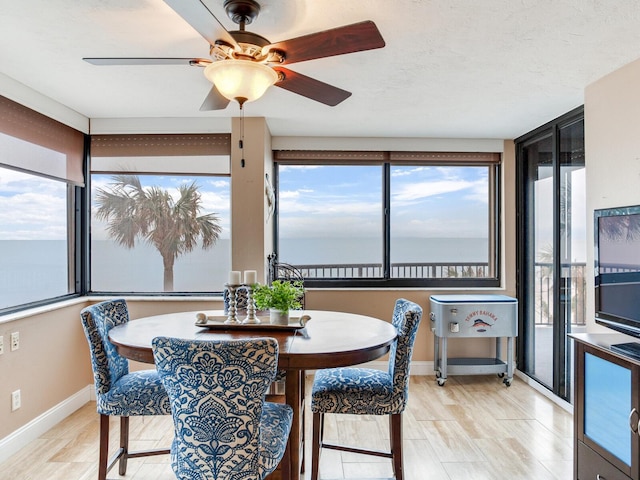 sunroom / solarium featuring a water view and ceiling fan