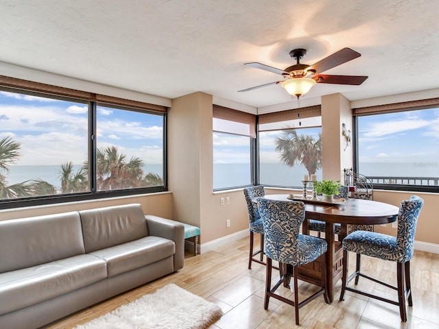 dining room featuring ceiling fan, a textured ceiling, and a water view