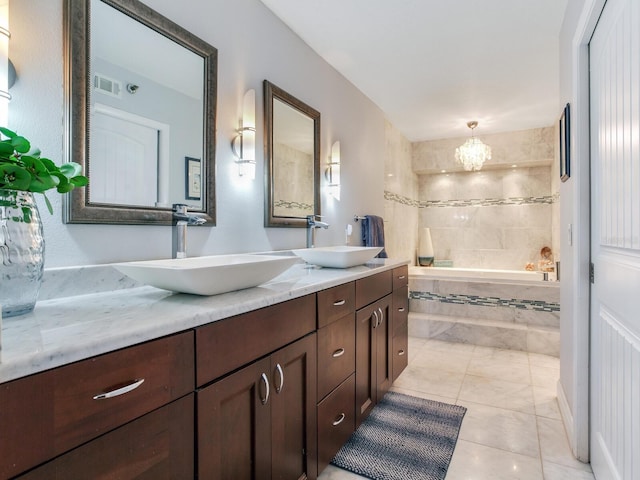 bathroom featuring vanity, tile patterned flooring, a notable chandelier, and tiled tub