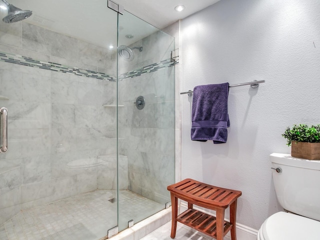 bathroom featuring toilet and a shower with shower door