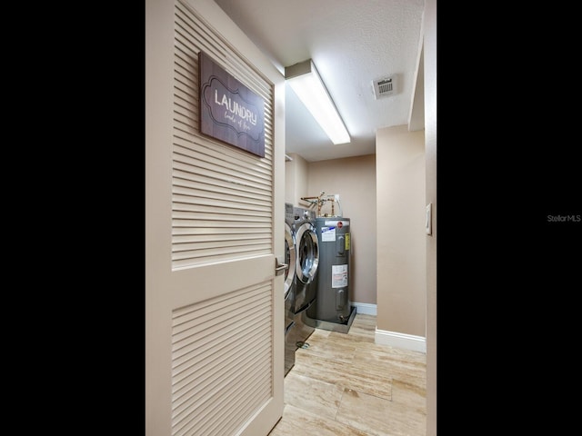 laundry room featuring water heater, independent washer and dryer, and a textured ceiling