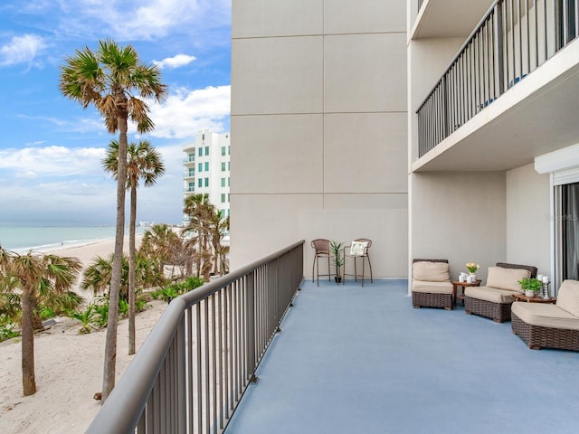 balcony with a water view and a view of the beach