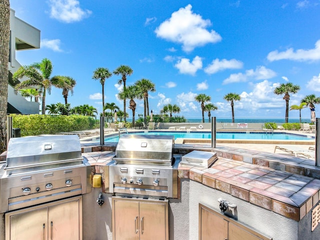 view of patio / terrace featuring exterior kitchen, a community pool, and grilling area