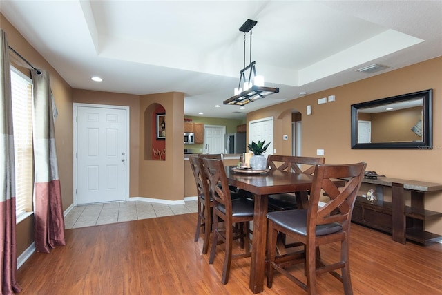 dining room featuring a raised ceiling and light hardwood / wood-style flooring