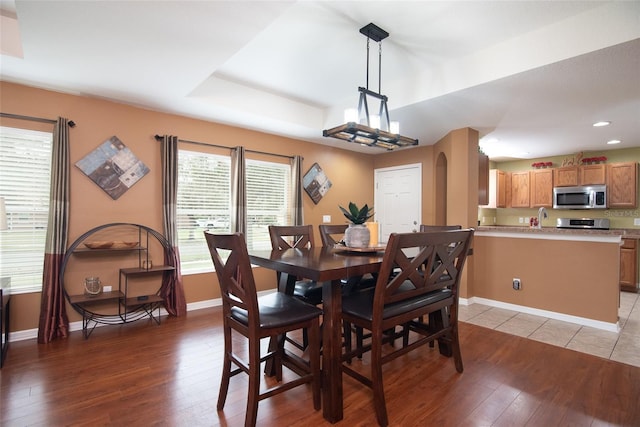 dining space with hardwood / wood-style floors and a tray ceiling