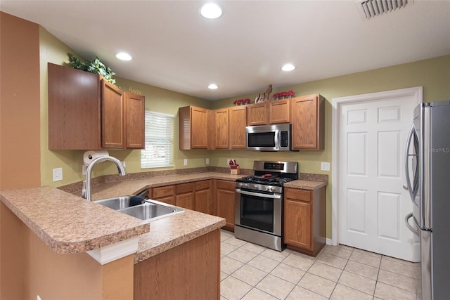 kitchen with appliances with stainless steel finishes, sink, light tile patterned flooring, and kitchen peninsula