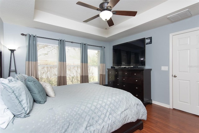 bedroom featuring a raised ceiling, ceiling fan, and dark hardwood / wood-style floors