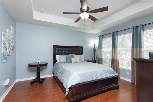 bedroom featuring dark hardwood / wood-style flooring, a raised ceiling, and ceiling fan