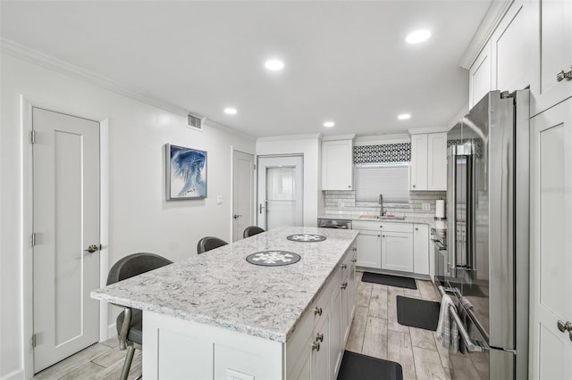 kitchen with tasteful backsplash, stainless steel appliances, wood finish floors, a kitchen bar, and a sink